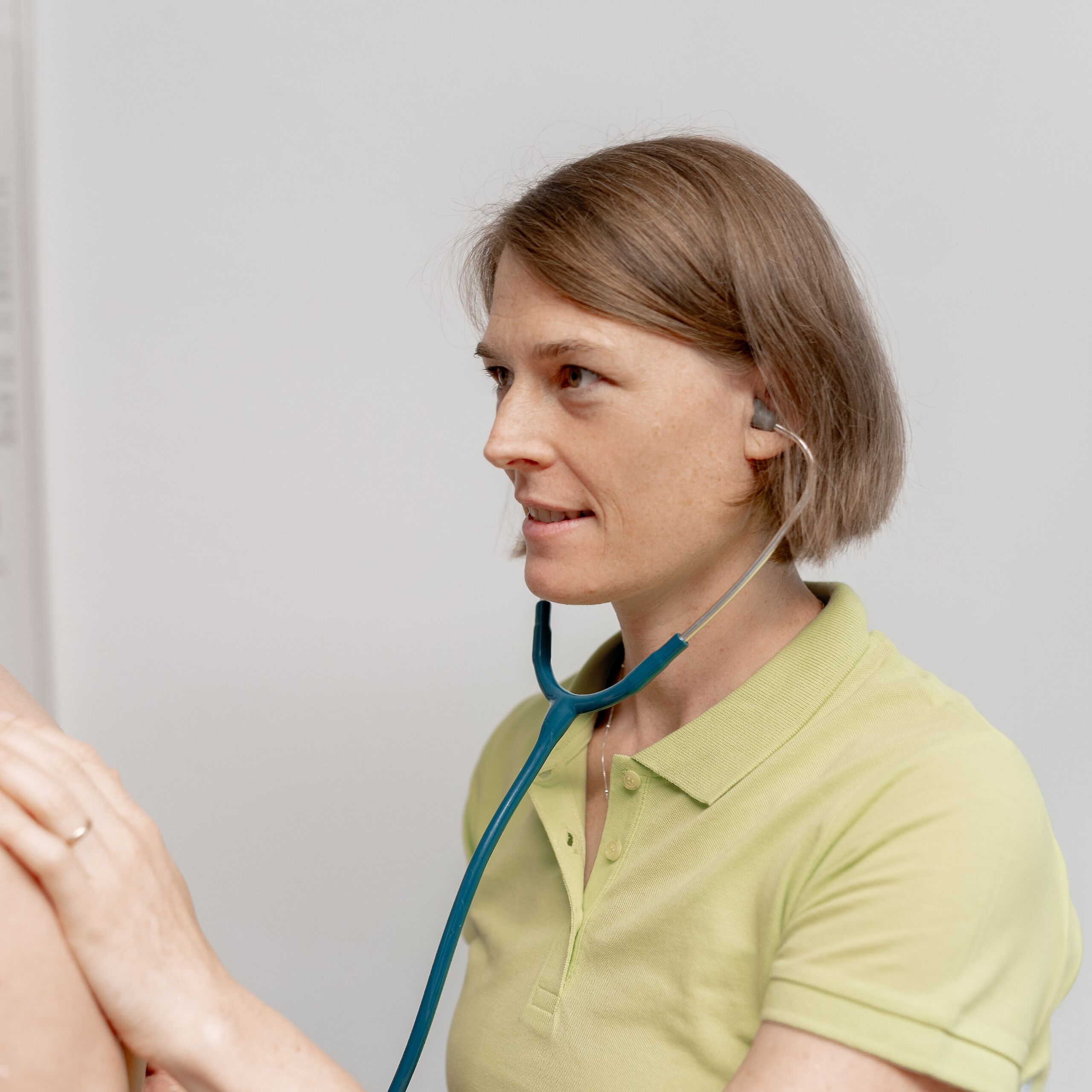 Ärztin hört mit Stethoskop die Lunge eines älteren Patienten ab